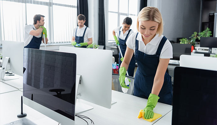 Cleaners in overalls wiping office desks