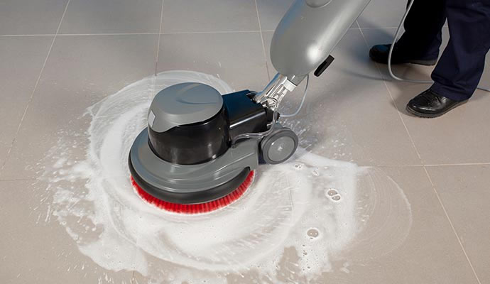 Person cleaning a tile floor with equipment