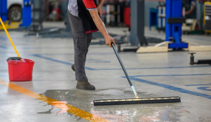 Industrial floor cleaning using squeegee by service provider