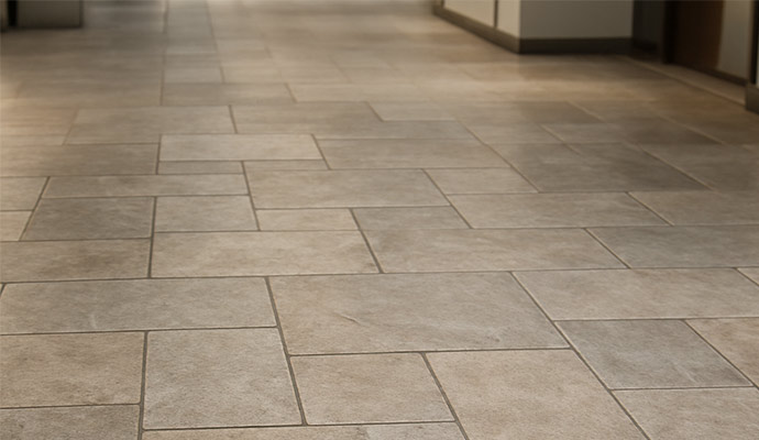 A wide hallway with large, rectangular neutral-toned stone floor tiles.