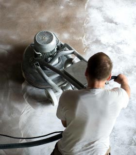 A professional cleaner operating floor grinding machine on a concrete surface