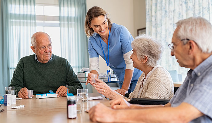 Caregiver assisting senior residents at table