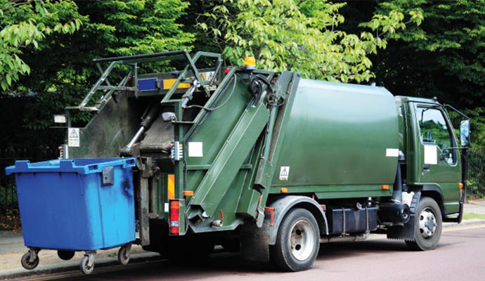 Rear loader garbage truck on road