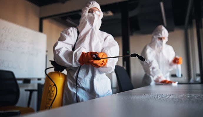 Two experts disinfecting desks in an office space