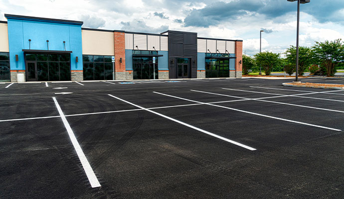A freshly paved black asphalt commercial parking lot in DeSoto with crisp, white painted stalls and handicap accessibility markings.