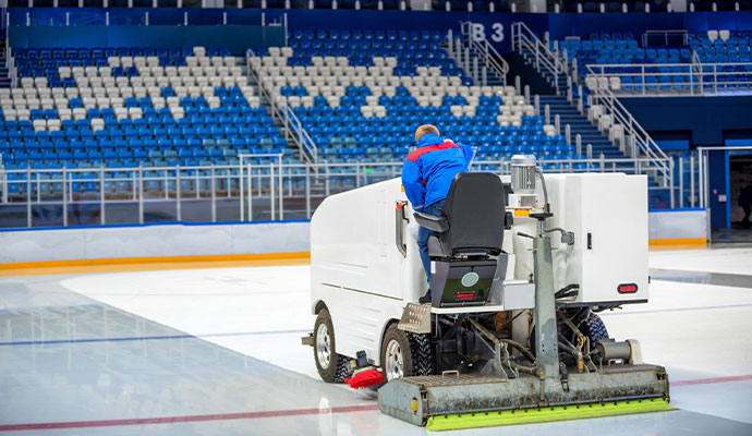An industrial floor scrubber on an indoor arena floor.