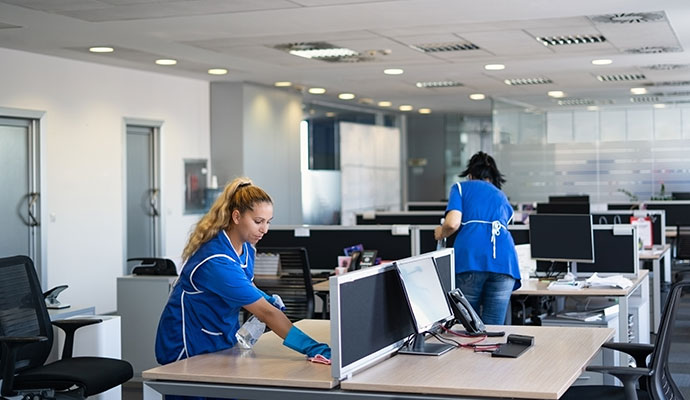 Two experts cleaning office desks in an office space